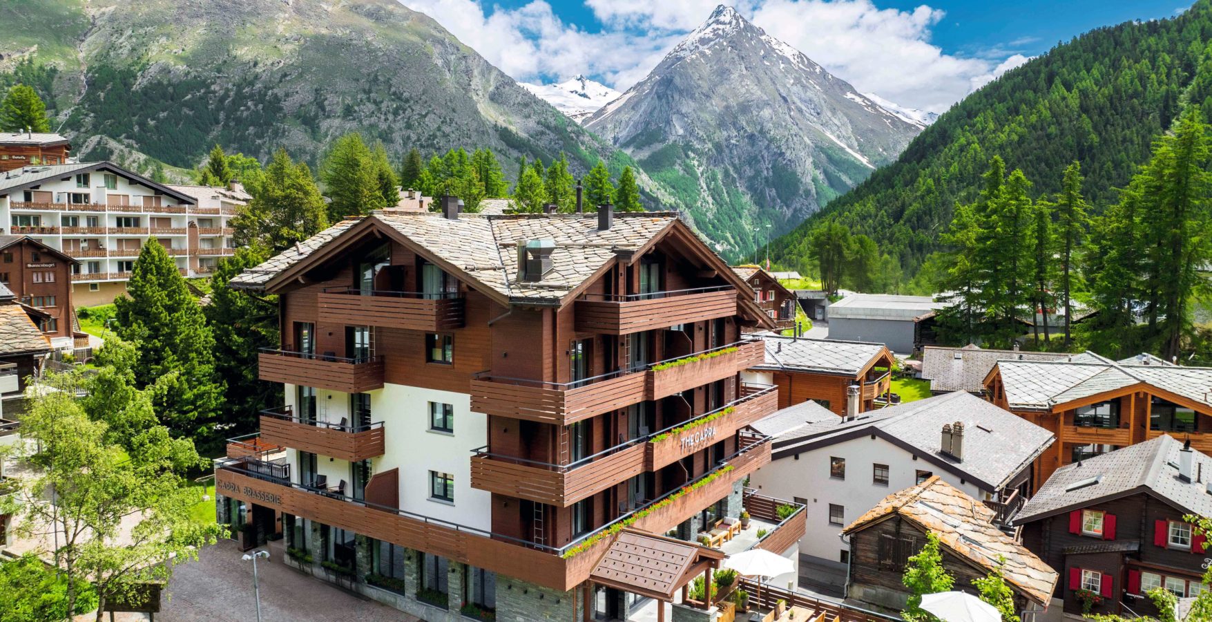 Façade du lodge alpin The Capra, au cœur du village piéton de Saas-Fee, entouré de montagnes enneigées. Marie Claire Suisse