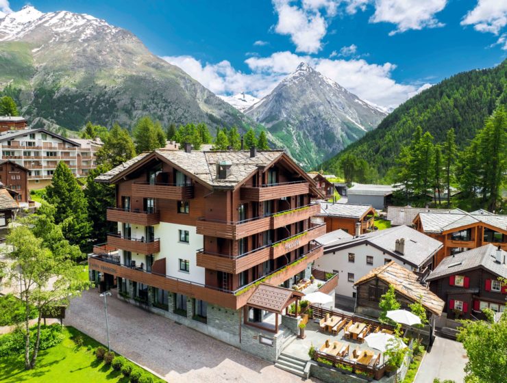 Façade du lodge alpin The Capra, au cœur du village piéton de Saas-Fee, entouré de montagnes enneigées. Marie Claire Suisse