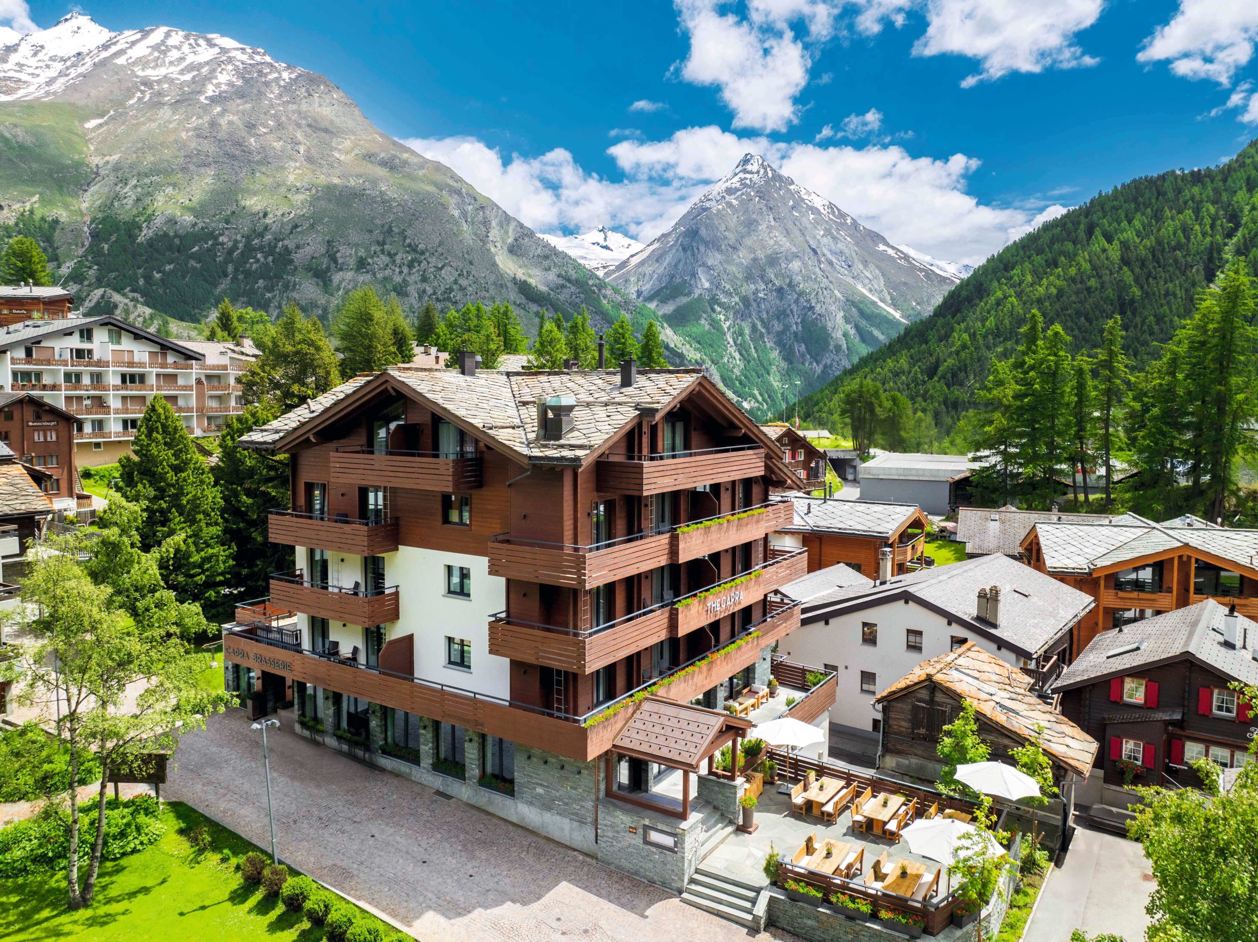 Façade du lodge alpin The Capra, au cœur du village piéton de Saas-Fee, entouré de montagnes enneigées. Marie Claire Suisse
