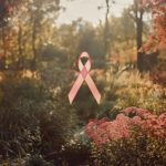 Ruban rose symbolisant la lutte contre le cancer du sein, flottant dans un jardin baigné de lumière automnale.