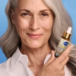 Femme présentant le sérum NIVEA Q10 Collagène Expert sur fond bleu