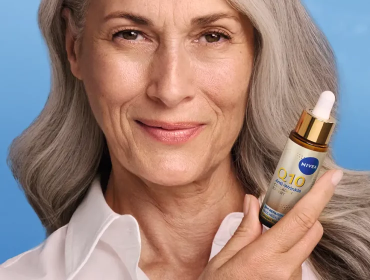 Femme présentant le sérum NIVEA Q10 Collagène Expert sur fond bleu