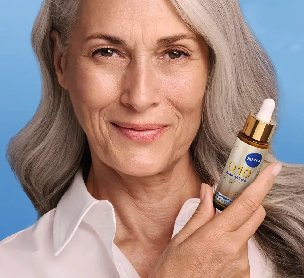 Femme présentant le sérum NIVEA Q10 Collagène Expert sur fond bleu